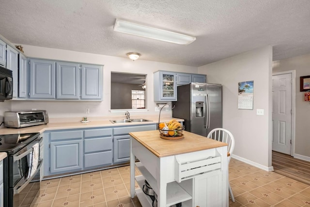 kitchen featuring a toaster, blue cabinetry, stainless steel appliances, and a sink