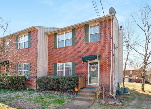 view of front of home featuring brick siding and central AC