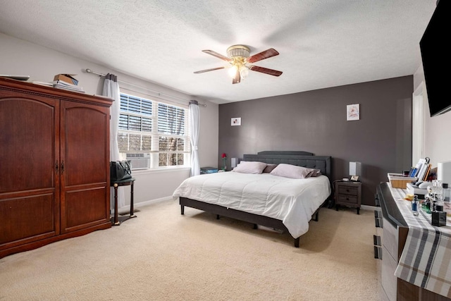 bedroom featuring baseboards, light carpet, a textured ceiling, and ceiling fan