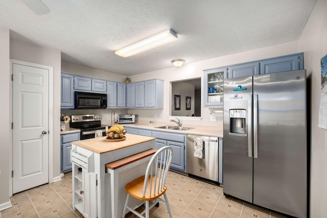 kitchen featuring wood counters, stainless steel appliances, blue cabinets, and a sink