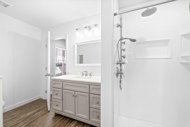 full bathroom featuring visible vents, toilet, tiled shower, wood finished floors, and vanity