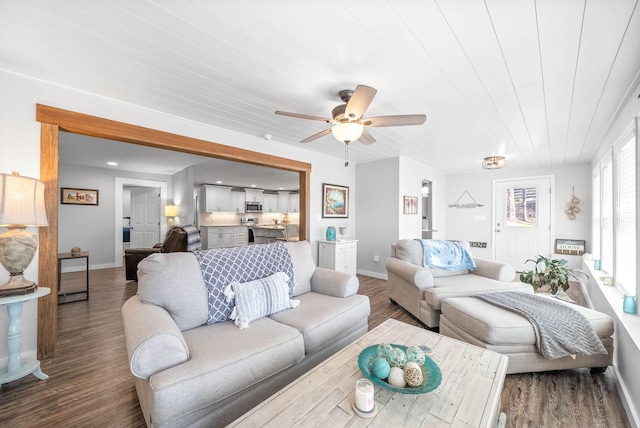 living area featuring dark wood-type flooring, a ceiling fan, and baseboards