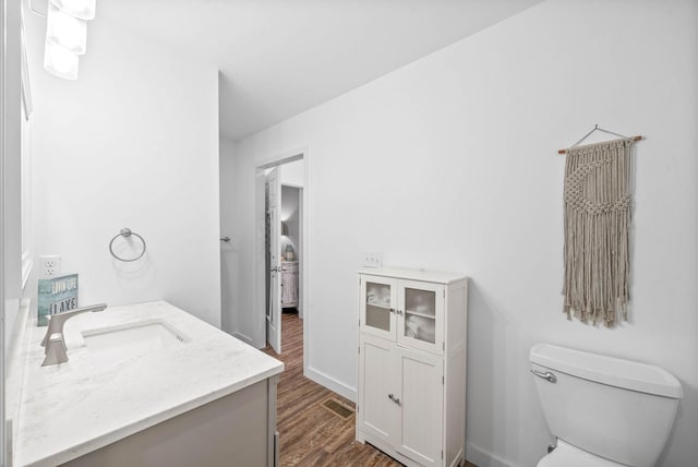 bathroom featuring vanity, wood finished floors, visible vents, baseboards, and toilet