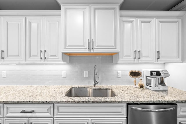 kitchen with a sink, backsplash, stainless steel dishwasher, and white cabinets