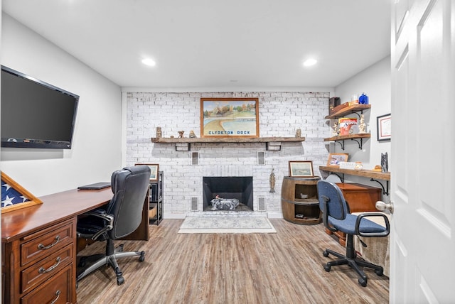 office space with recessed lighting, a brick fireplace, and wood finished floors