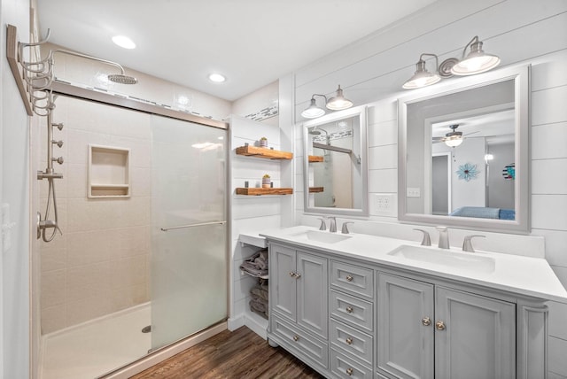 ensuite bathroom with a shower stall, connected bathroom, wood finished floors, and a sink