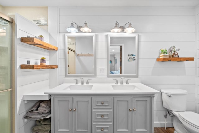 full bathroom with a sink, an enclosed shower, toilet, and double vanity
