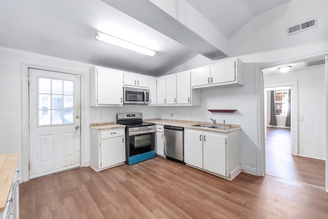 kitchen featuring visible vents, vaulted ceiling, light wood-style flooring, stainless steel appliances, and a sink