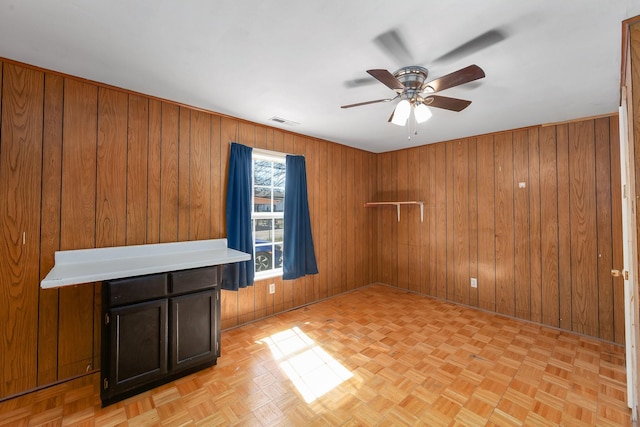 spare room with visible vents, wood walls, and ceiling fan