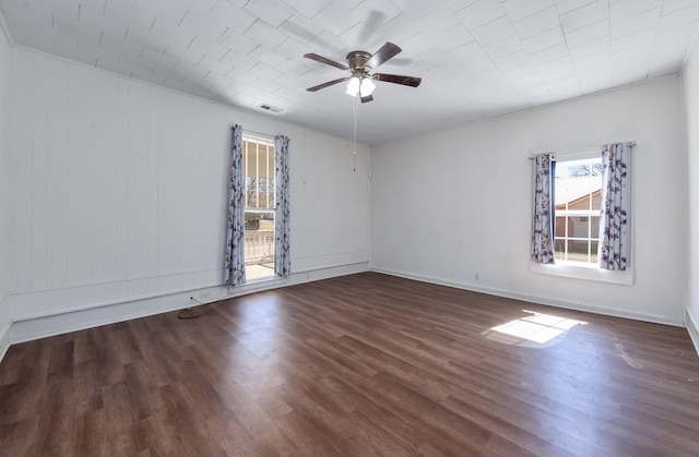 spare room featuring ceiling fan, visible vents, baseboards, and wood finished floors