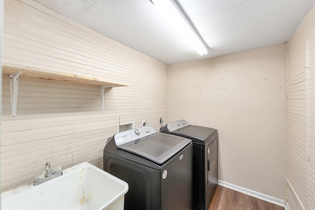 laundry room featuring wood finished floors, baseboards, laundry area, a sink, and independent washer and dryer