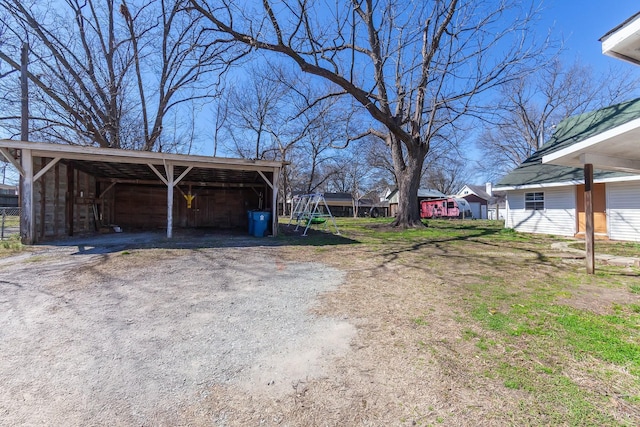 view of yard featuring a detached carport, an outbuilding, and driveway