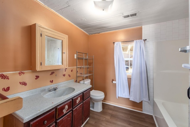 bathroom featuring visible vents, baseboards, toilet, wood finished floors, and vanity