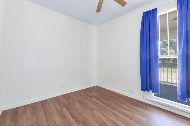 unfurnished room with baseboards, dark wood finished floors, and a ceiling fan