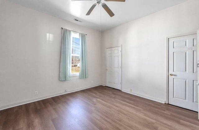 unfurnished room featuring visible vents, wood finished floors, baseboards, and ceiling fan