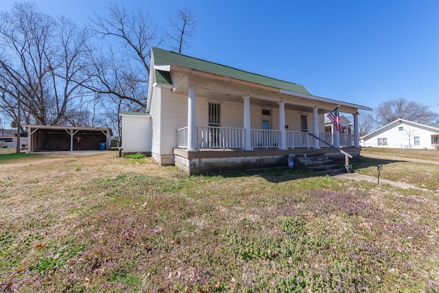 view of front of property with a carport, covered porch, a front yard, and roof with shingles