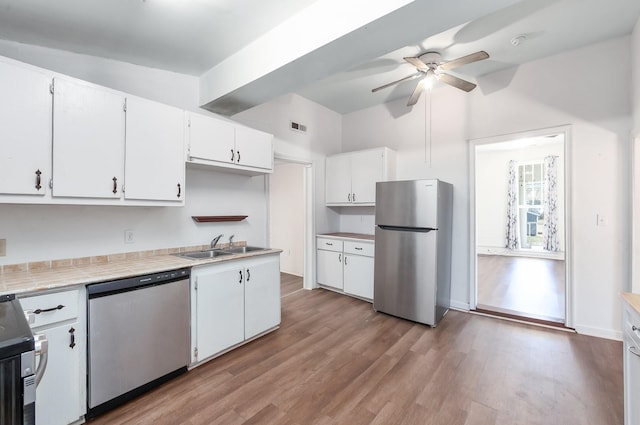 kitchen with visible vents, wood finished floors, white cabinetry, tile countertops, and stainless steel appliances