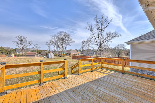 wooden deck featuring a yard, an outbuilding, a storage shed, and fence