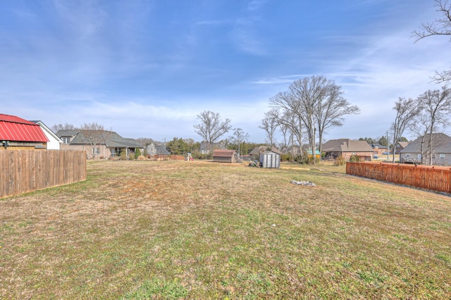 view of yard featuring a shed, a residential view, an outdoor structure, and fence