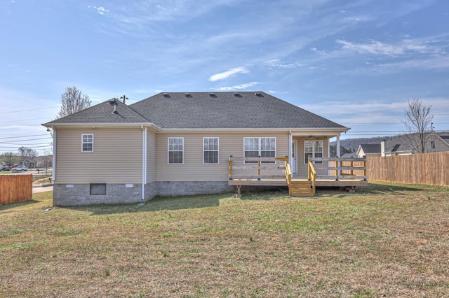 rear view of house featuring fence, a shingled roof, crawl space, a deck, and a lawn