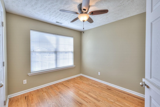 spare room with light wood finished floors, visible vents, baseboards, ceiling fan, and a textured ceiling