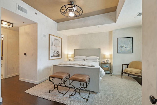 bedroom with visible vents, baseboards, and wood finished floors