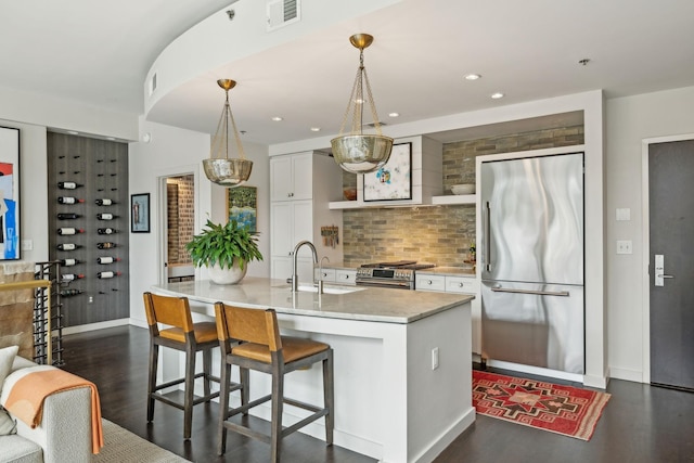 kitchen featuring visible vents, dark wood finished floors, premium appliances, white cabinets, and a sink