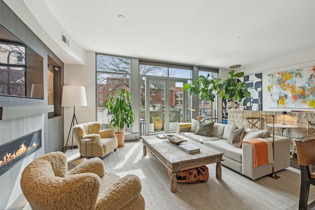 living room featuring a glass covered fireplace, a wall of windows, and visible vents