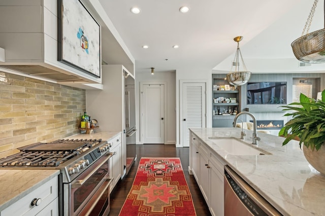 kitchen featuring white cabinets, light stone countertops, appliances with stainless steel finishes, and a sink