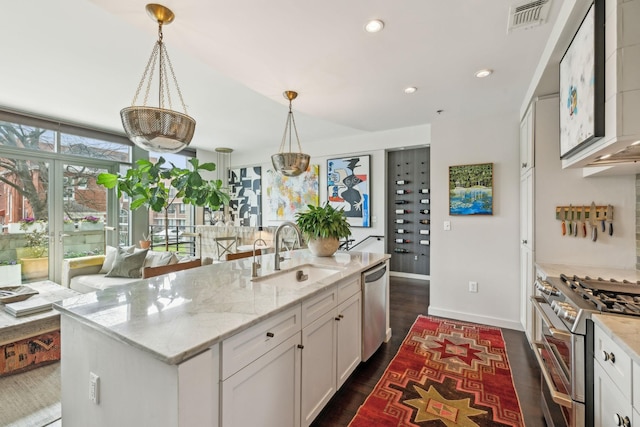 kitchen with visible vents, light stone countertops, appliances with stainless steel finishes, dark wood-style floors, and a sink