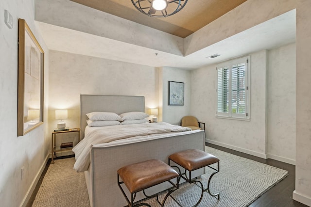 bedroom with visible vents, baseboards, and wood finished floors