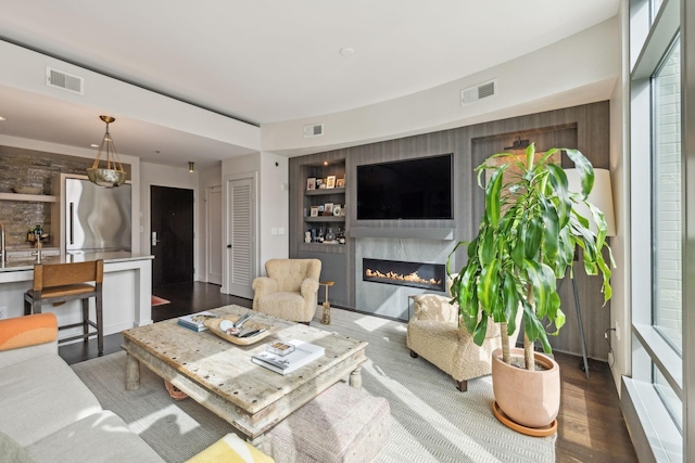 living room with a premium fireplace, visible vents, and built in features