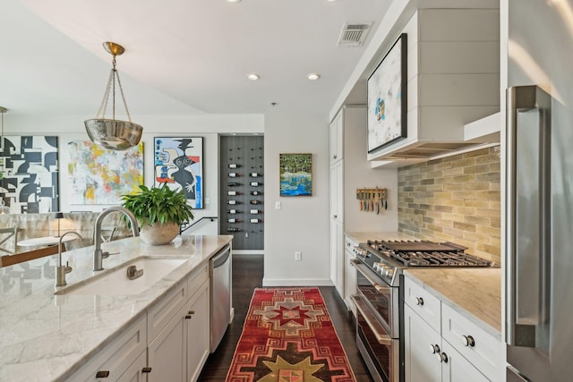 kitchen featuring tasteful backsplash, visible vents, dark wood-type flooring, stainless steel appliances, and a sink