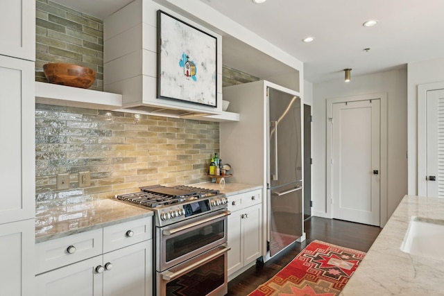 kitchen featuring tasteful backsplash, dark wood-type flooring, light stone counters, white cabinets, and stainless steel appliances