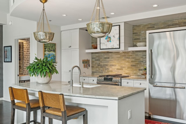 kitchen with a sink, tasteful backsplash, white cabinetry, appliances with stainless steel finishes, and light stone countertops