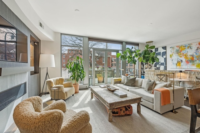 living room featuring expansive windows, visible vents, and a glass covered fireplace