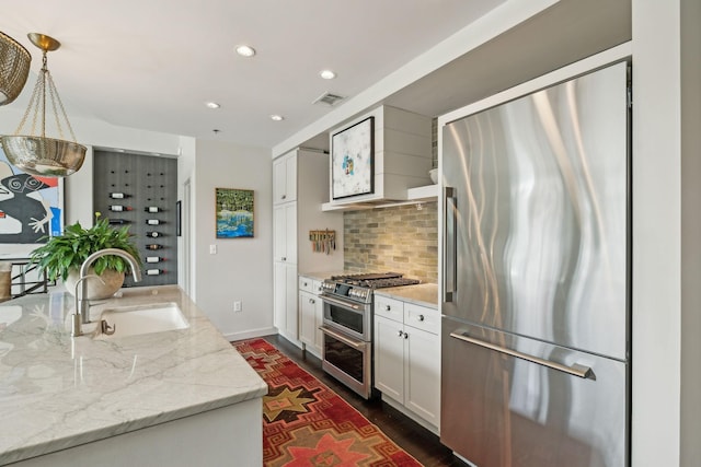 kitchen with custom range hood, a sink, tasteful backsplash, white cabinetry, and appliances with stainless steel finishes