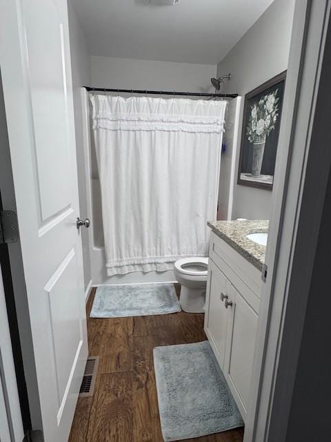 full bathroom with vanity, wood finished floors, visible vents, shower / bath combo, and toilet