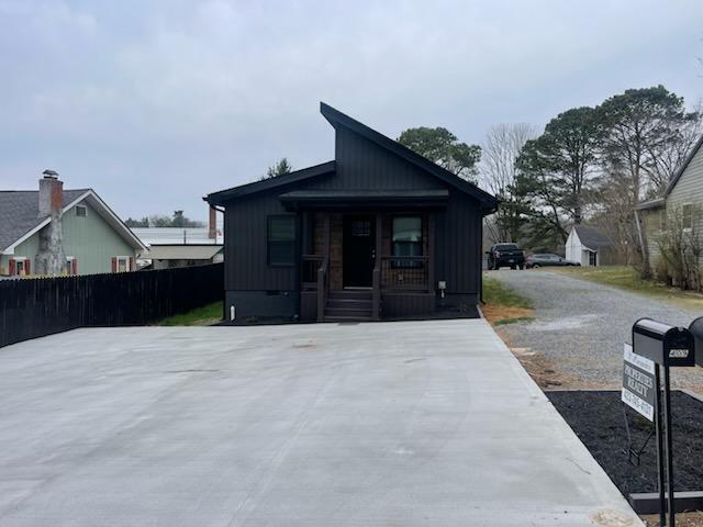 view of front of house with a porch, concrete driveway, and fence