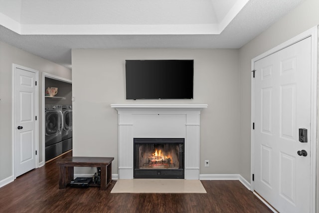 living room with a textured ceiling, wood finished floors, a lit fireplace, and separate washer and dryer