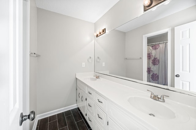 full bath with double vanity, wood tiled floor, baseboards, and a sink