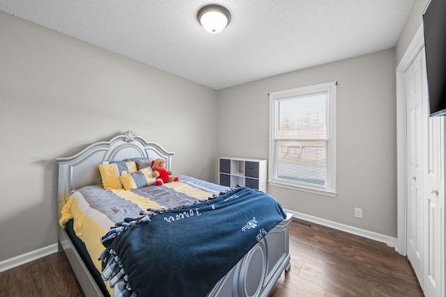 bedroom featuring visible vents, baseboards, a textured ceiling, and wood finished floors