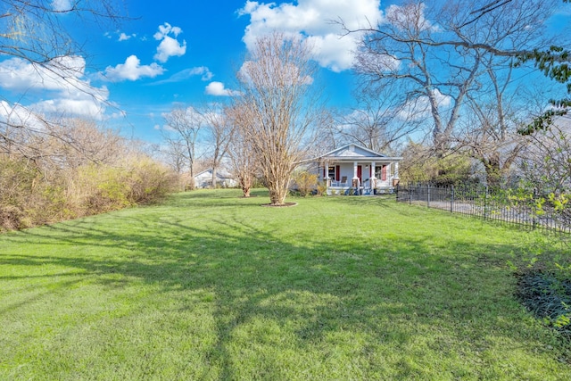 view of yard with covered porch and fence