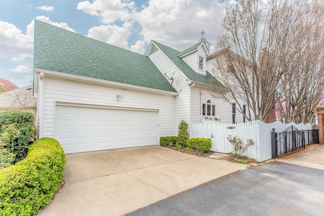 view of front of home with a gate, driveway, roof with shingles, a garage, and a fenced front yard