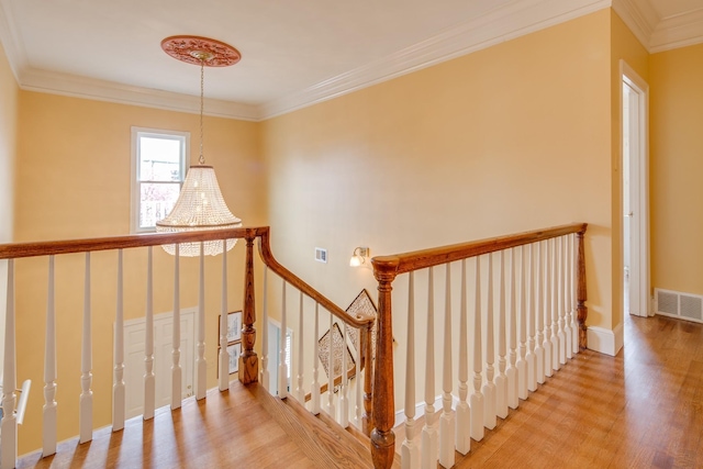 stairs with visible vents, baseboards, wood finished floors, and ornamental molding