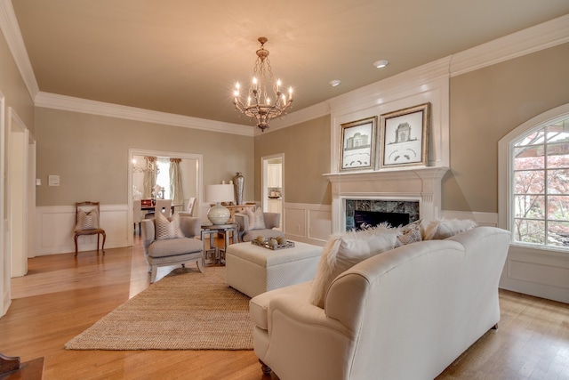 living area with light wood-style flooring, a chandelier, a fireplace, and a decorative wall