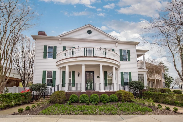 neoclassical / greek revival house featuring a balcony, a porch, and a chimney