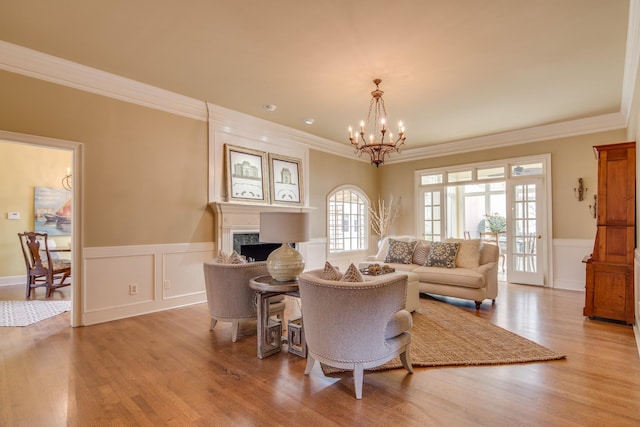 living area featuring wainscoting, a fireplace, an inviting chandelier, and wood finished floors