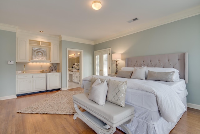 bedroom featuring visible vents, baseboards, ornamental molding, light wood-style flooring, and ensuite bathroom