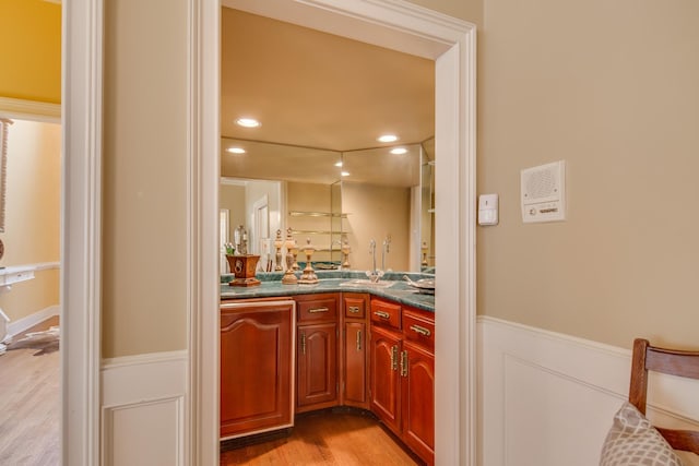 bar featuring recessed lighting, light wood-style flooring, wainscoting, and a decorative wall